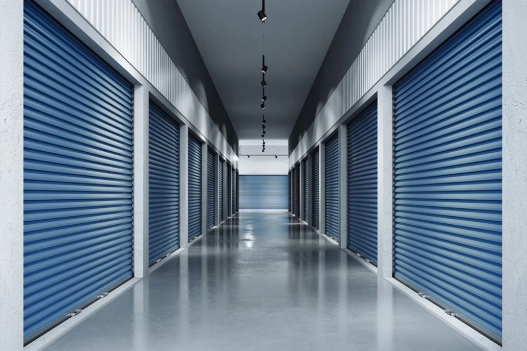 Indoor hallway at Pacific Rim Storage’s Victoria facility with clean blue roll-up storage doors and polished flooring.