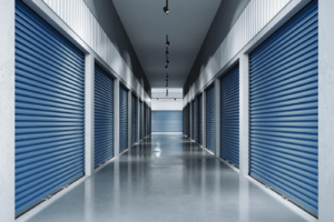 Indoor hallway at Pacific Rim Storage’s Victoria facility with clean blue roll-up storage doors and polished flooring.